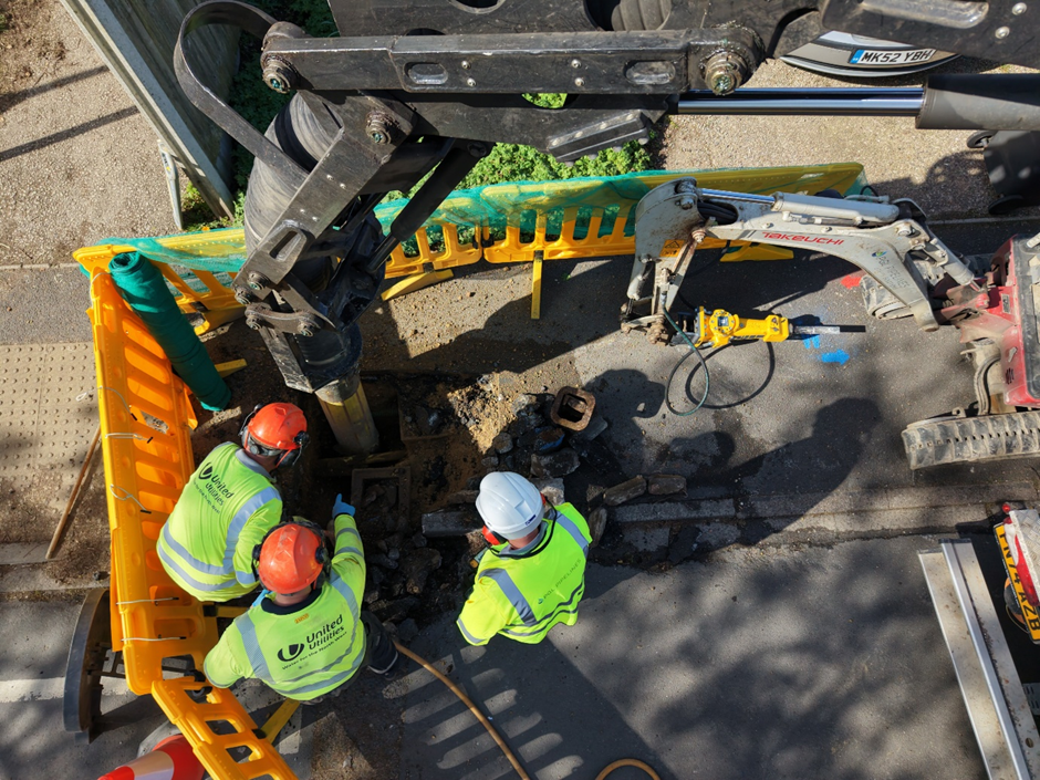 Workers digging up a road to expose pipes